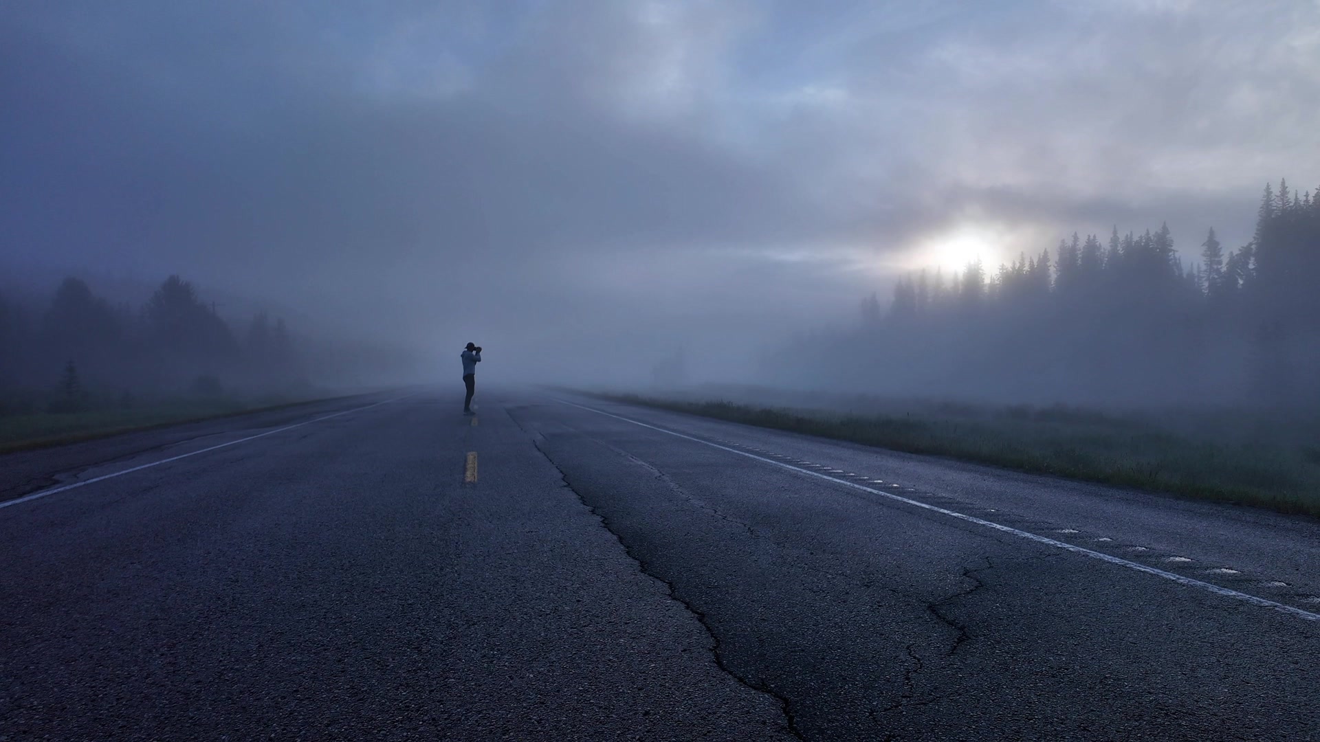 Photographer alone on a misty pre-dawn road — frame from a brand-film capture